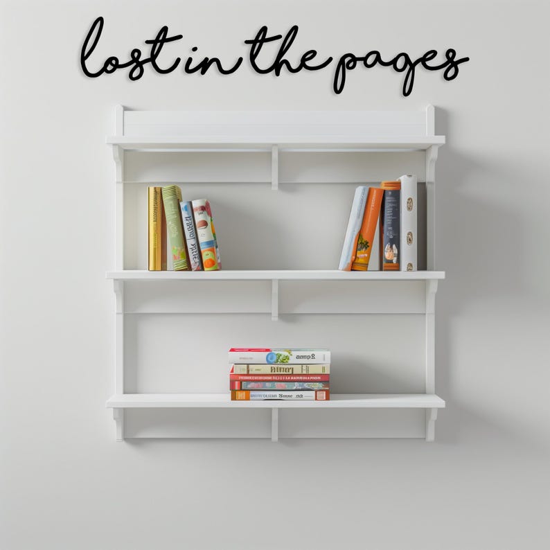 May include: A white wall-mounted bookshelf with three shelves, holding a collection of books. The phrase "lost in the pages" is written in black script above the shelves. The books have colorful spines.