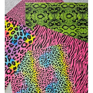 Könnte beinhalten: Eine Sammlung farbenfroher Stoffmuster mit Tiermotiven. Die Drucke umfassen neonrosa Leopardenmuster, grüne Schlangenmuster, rosa Zebrastreifen und einen Regenbogen-Leoparden-Print. Die Muster sind auf einer grauen Oberfläche angeordnet.