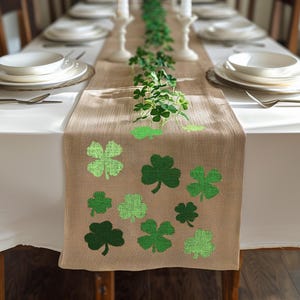 May include: A brown burlap table runner with green shamrock designs. The runner is decorated with a garland of green shamrocks.