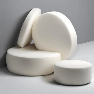 May include: Four white foam cushions of different sizes stacked on top of each other. The cushions are round and have a smooth surface.