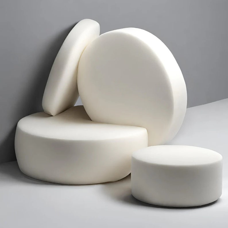 May include: Four white foam cushions of different sizes stacked on top of each other. The cushions are round and have a smooth surface.