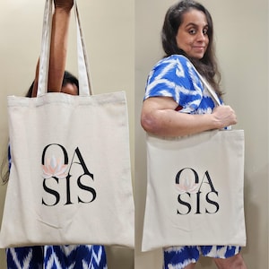 Puede incluir: Una bolsa de lona blanca con texto negro que dice "OASIS" y un gr&aacute;fico de flor rosa.