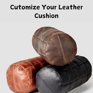 May include: Three leather cushions in brown, orange, and black. Each cushion is made of stitched leather panels and has a cylindrical shape.