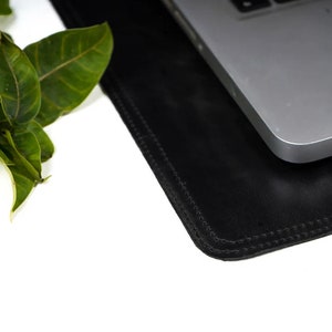 Black leather desk mat under a laptop with a plant