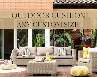 May include: Wicker outdoor furniture set with beige cushions and striped accent pillows. A matching coffee table holds drinks and fruit. The text "OUTDOOR CUSHION - ANY CUSTOM SIZE" is displayed at the top of the image.