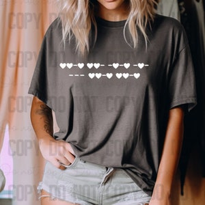 May include: A gray t-shirt with a white graphic of a row of hearts and dashes. The graphic reads "--- ♥♥♥ --- ♥♥♥ --- ♥♥♥ --- ♥♥♥ --- ♥♥♥ ---"
