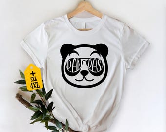 May include: White t-shirt with a black panda face design wearing sunglasses, with the word "PANDAS" in the lenses. The shirt hangs on a wooden hanger. A yellow tag indicates 3XL and 4XL sizes.
