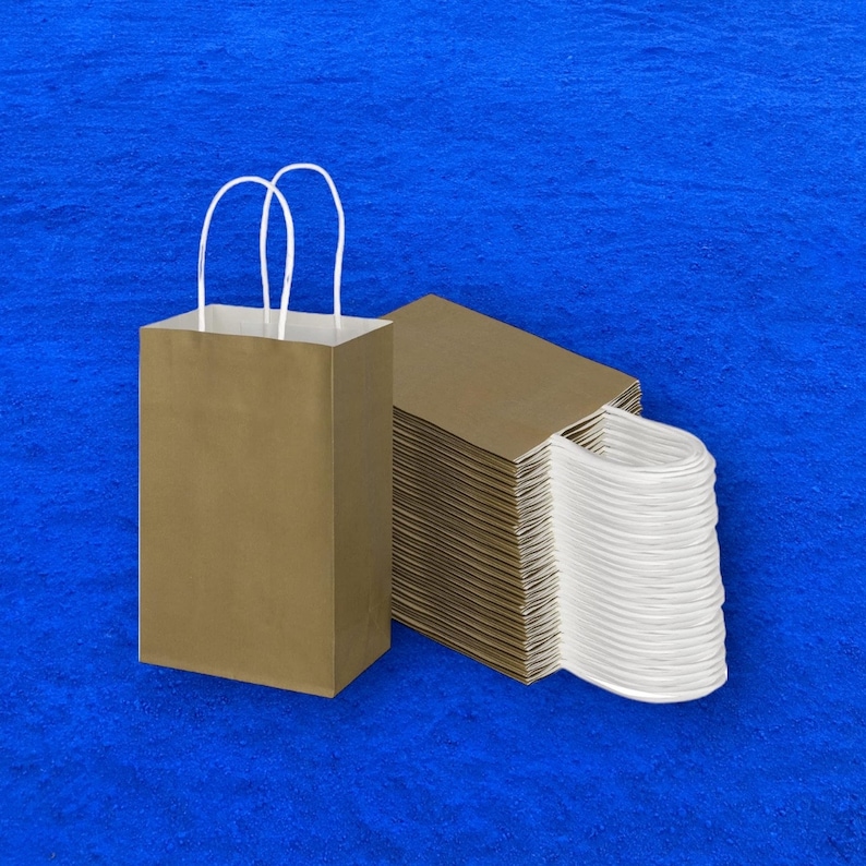 Op de afbeelding: Een stapel bruine papieren zakken met witte handvatten. De zakken zijn netjes gestapeld, met de handvatten naar buiten. De zakken liggen op een blauw oppervlak.