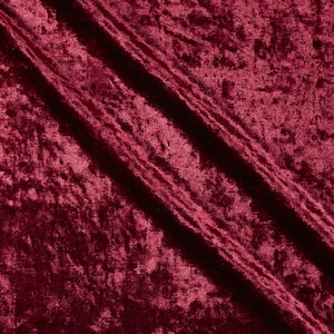 May include: Close-up of a deep burgundy crushed velvet fabric. The fabric has a soft, textured appearance with visible folds and shadows, creating a rich, luxurious look. The colour is a dark, saturated red with hints of purple.