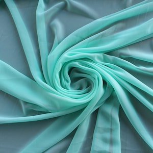 May include: A soft, flowing piece of turquoise fabric draped and gathered in a swirl pattern.