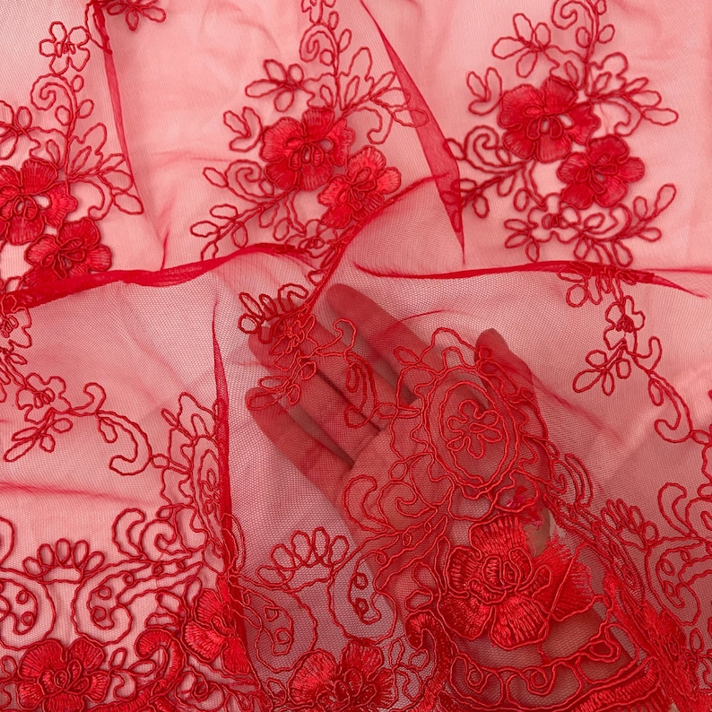 May include: Red sheer fabric with delicate floral embroidery. The fabric is soft and lightweight, making it perfect for a variety of projects.