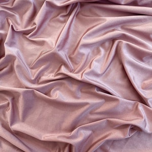 May include: A close-up of a soft, smooth, and silky fabric in a dusty rose colour. The fabric is draped and folded, creating a luxurious and elegant look.