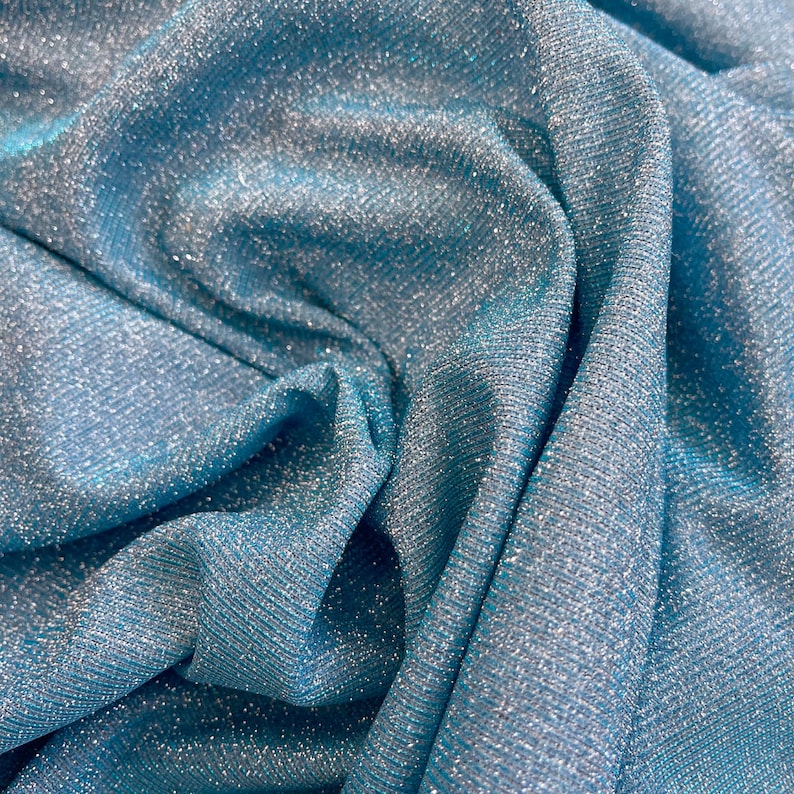 May include: Close-up of a blue fabric with a sparkly, iridescent finish. The fabric has a subtle ribbed texture.
