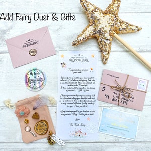 Peut inclure: Ensemble de cadeaux et de papeterie sur le th&egrave;me des f&eacute;es. Comprend une baguette &eacute;toile dor&eacute;e, une enveloppe rose, une lettre, une pochette avec des bibelots et un autocollant "My Tooth is Sparkling". Le texte "Add Fairy Dust & Gifts" est en haut.