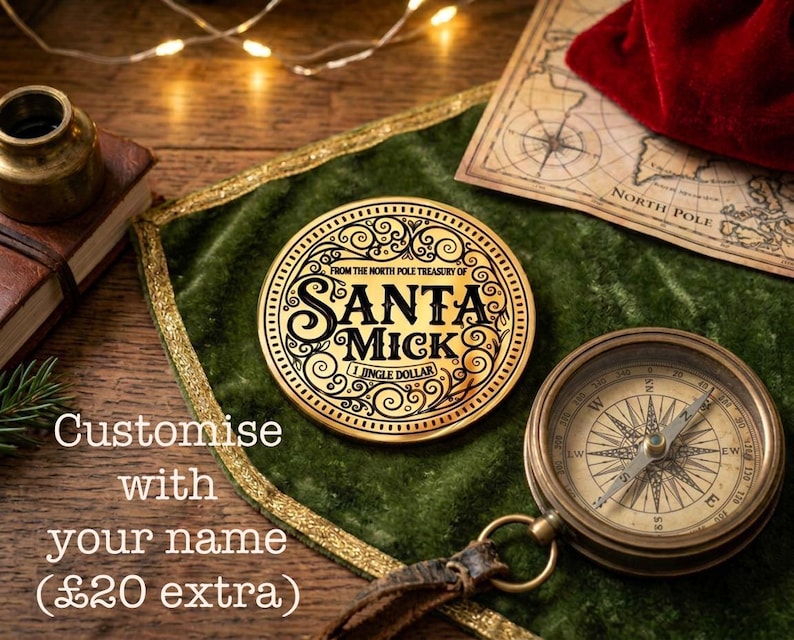 Puede incluir: Una moneda dorada con el texto "SANTA MICK" y "1 JINGLE DOLLAR" sobre una superficie de terciopelo verde, junto a una br&uacute;jula y un mapa. La moneda forma parte del "North Pole Treasury". La imagen tambi&eacute;n incluye el texto "Customise with your name".