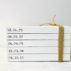 May include: A stack of five white books with dates printed on the front. The books are tied together with twine.