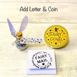May include: A whimsical fairy-themed set featuring a small glass bottle filled with colorful glitter, labeled "Fairy Dust." Includes a gold-colored coin with "Fairy Gold" text and a small white envelope with "Fairy Mail" text.