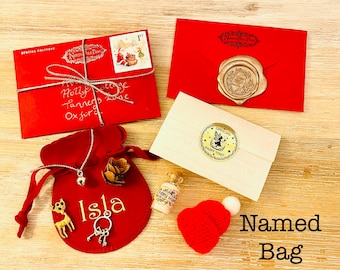 May include: A collection of festive items, including a red velvet bag with the name "Isla", a red envelope with a silver string, and a small red hat. Other items include a small bottle and a cream-colored envelope with a fairy sticker.