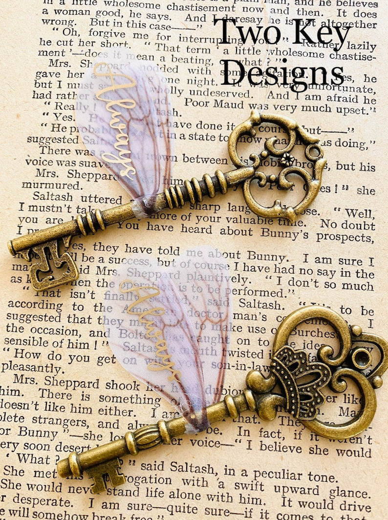 May include: Two antique keys with ornate designs, one with a crown, on a page of a book with the text "Two Key Designs".
