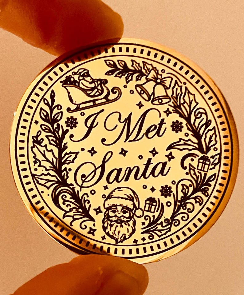 Puede incluir: Un adorno navide&ntilde;o redondo de color dorado con el texto "I Met Santa". El adorno presenta un dise&ntilde;o detallado de Pap&aacute; Noel en su trineo, campanas, regalos y follaje festivo. El dise&ntilde;o es en negro.