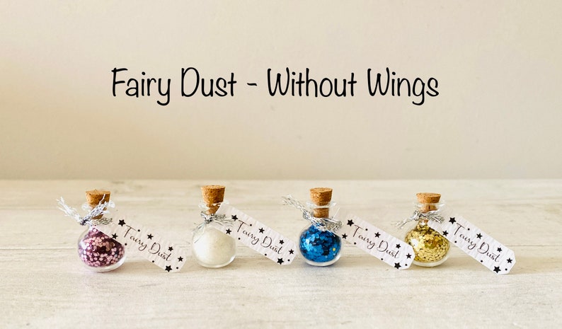 May include: Four small glass bottles with cork stoppers, each filled with a different color of glitter. The bottles are labeled "Fairy Dust" and are tied with silver ribbon. The text "Fairy Dust - Without Wings" is above the bottles.