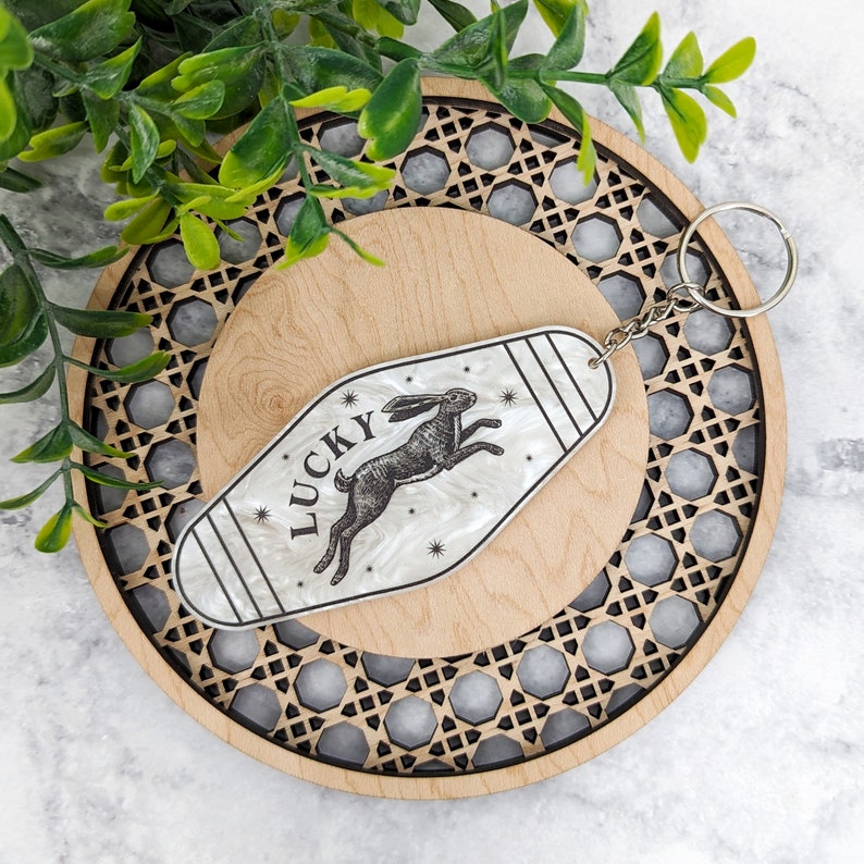 Retro Motel shaped keychain with rabbit running design, stars and the word "Lucky" on top of the rabbit
