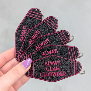 May include: A set of five black glitter motel-style keychains with pink trim and lettering. Four keychains feature the word ALWAYS, while the fifth keychain displays the text ALWAYS CLAM CHOWDER. Each keychain includes a silver metal split ring.