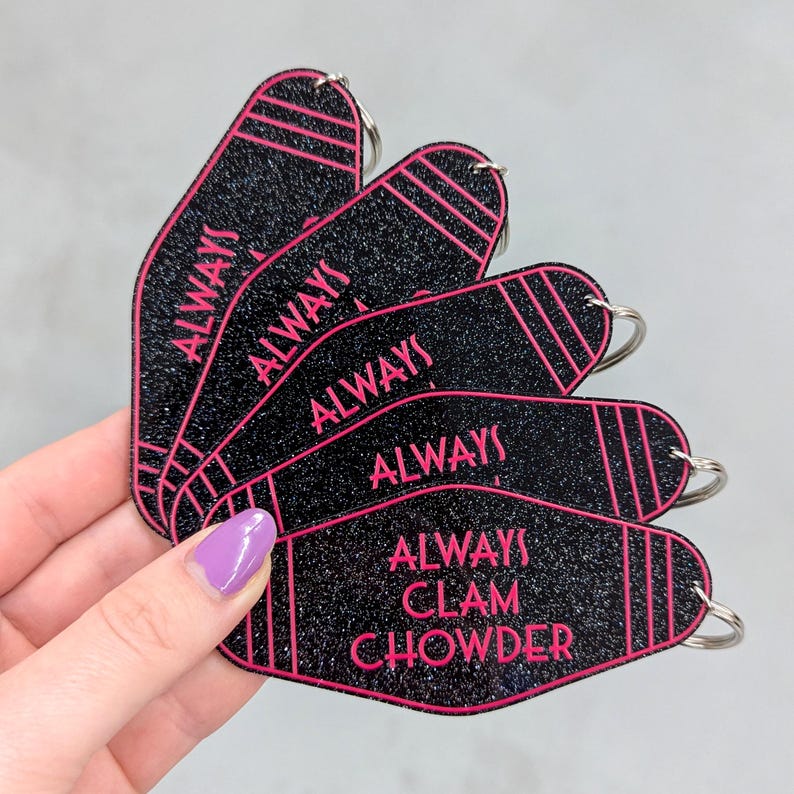 May include: A set of five black glitter motel-style keychains with pink trim and lettering. Four keychains feature the word ALWAYS, while the fifth keychain displays the text ALWAYS CLAM CHOWDER. Each keychain includes a silver metal split ring.