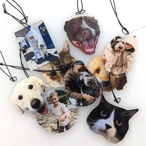 Puede incluir: Una colecci&oacute;n de adornos fotogr&aacute;ficos personalizados transparentes con varias mascotas y personas. Los adornos muestran im&aacute;genes de perros, gatos e individuos, cada uno con una forma &uacute;nica y una cuerda negra para colgar. Las fotos est&aacute;n impresas en pl&aacute;stico transparente.