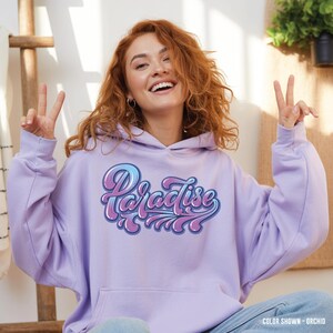 May include: A lilac hoodie with the word "Paradise" in a retro font, featuring blue and purple gradients. The hoodie has a front pocket and a hood. The colour is described as "Orchid".