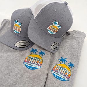 May include: A white ceramic mug with a black handle and the text "But First, Coffee" in a bold, black font. The mug is set against a blurred background, suggesting a cosy setting.