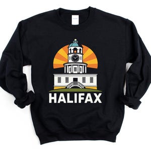 Puede incluir: Sudadera negra con un gráfico colorido de la torre del reloj de la Ciudadela de Halifax con un diseño de sol naciente. La palabra "HALIFAX" está impresa en blanco. Una prenda superior cómoda e informal.