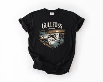 May include: Black t-shirt featuring a graphic of the Gullfoss waterfall in Iceland. The design includes the text "Gullfoss Iceland" above the waterfall illustration. The shirt is made of a soft material.