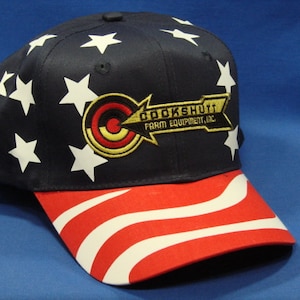 May include: A blue and red baseball cap with white stars and stripes. The cap has a gold embroidered logo that says "Crookshutt Farm Equipment, Inc."