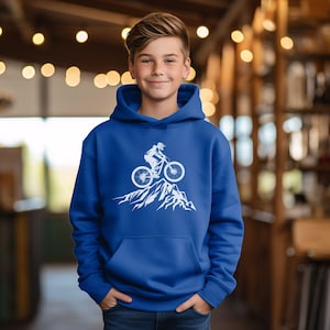 May include: A royal blue hoodie featuring a white graphic of a mountain biker on a mountain peak. The hoodie has a hood and a front pocket. The image is a simple, clean design.