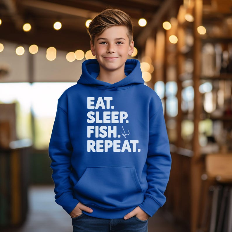 May include: A royal blue hooded sweatshirt with white text that reads 'Eat. Sleep. Fish. Repeat.' with a fishing hook symbol next to the word 'Fish.'