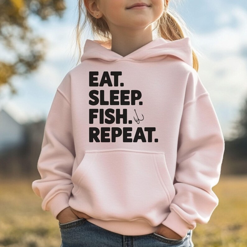 May include: Pink hooded sweatshirt with the text "EAT. SLEEP. FISH. REPEAT." in black lettering. A fishing hook symbol is next to the word "FISH."
