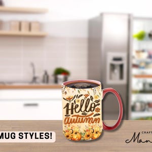 Könnte beinhalten: Eine Keramik-Kaffeetasse mit rotem Henkel und einem Herbst-Design. Die Tasse zeigt den Text "Hello Autumn" mit einem Blumen- und Kürbis-Design.