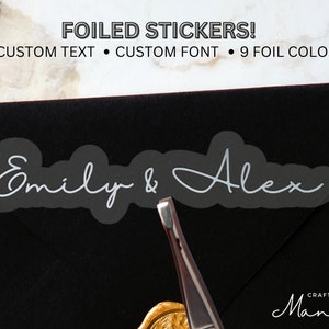 Puede incluir: Una pegatina de lámina plateada con el texto "Emily & Alex" sobre un fondo negro. La pegatina es un diseño personalizado con una fuente de escritura a mano.