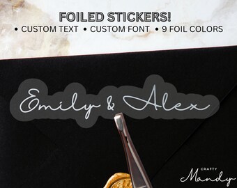Könnte beinhalten: Ein silberner Folienaufkleber mit dem Text "Emily & Alex" auf schwarzem Hintergrund. Der Aufkleber ist ein individuelles Design mit einer handschriftlichen Schriftart.