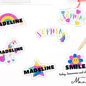 Peut inclure: Un ensemble d'autocollants colorés avec différents motifs, dont un arc-en-ciel, une licorne, une étoile, une fleur et les noms "Madeline" et "Sophia". Les autocollants ont un style fantaisiste et ludique.