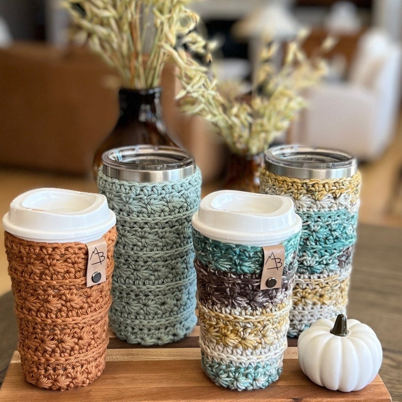 Pu&ograve; includere: Quattro fodere per tazze da caff&egrave; all'uncinetto in diversi colori e motivi. Le fodere sono realizzate con una variet&agrave; di punti e colori, tra cui marrone, verde e bianco. Tutte le fodere sono decorate con un'etichetta in pelle con le lettere "AB" su di esse.