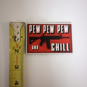 May include: Red and white patch with a black silhouette of a rifle and the text "PEW PEW PEW AND CHILL".