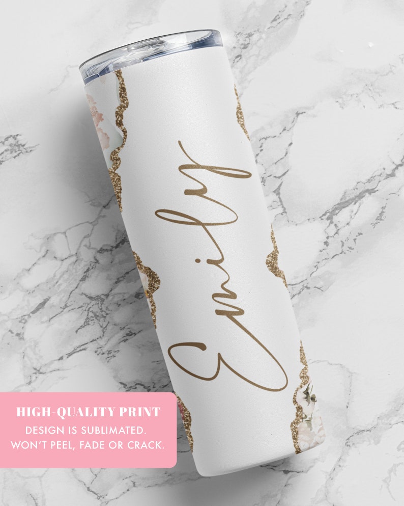 May include: White stainless steel tumbler with a gold glitter and floral design. The tumbler has the name "Emily" written in cursive on the front.
