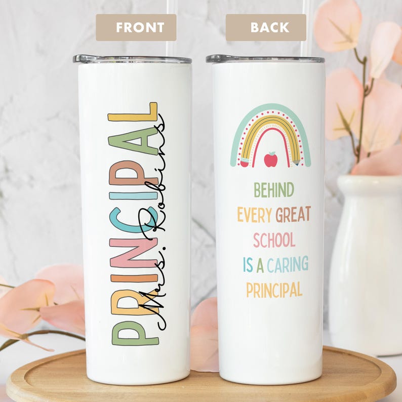 May include: White tumbler with a rainbow and pencils design. The text reads "Behind every great school is a caring principal". The front of the tumbler has the text "Principal Mrs. Robins" in colorful letters.