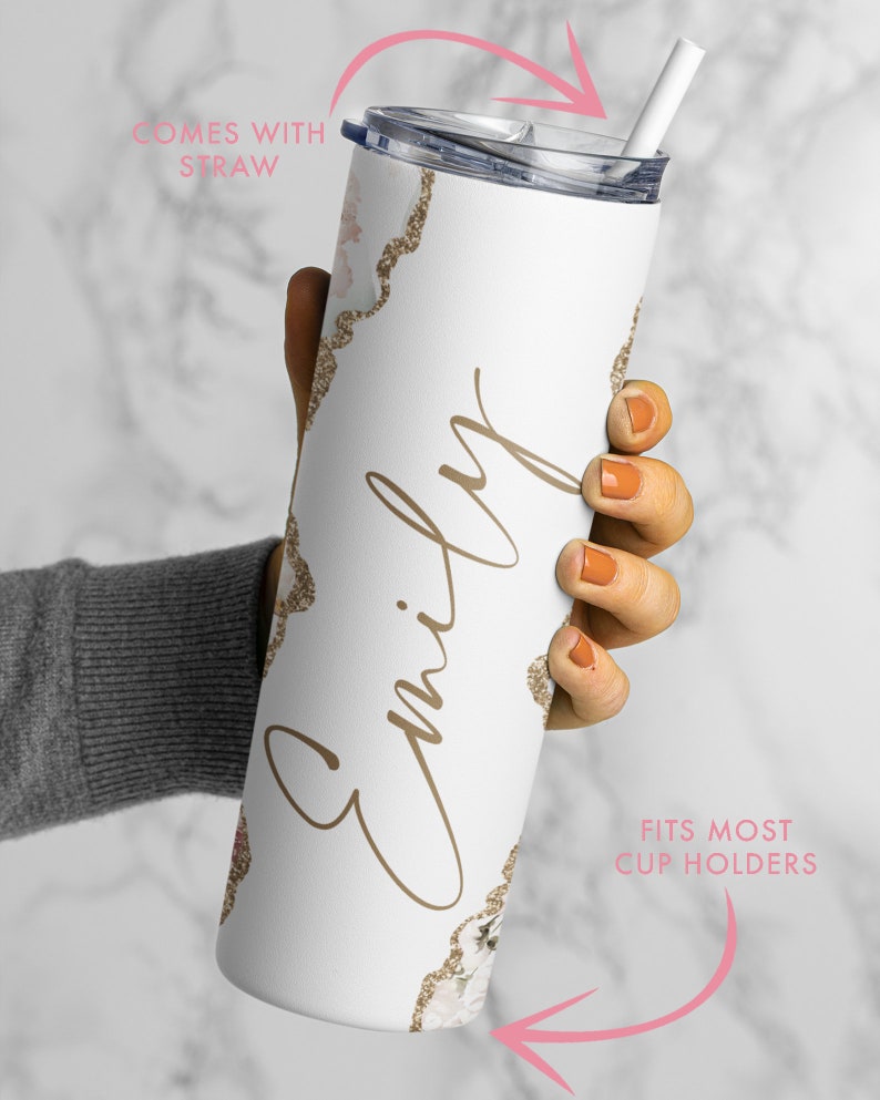 May include: White stainless steel tumbler with a gold glitter design and the name "Emily" written in cursive. The tumbler comes with a straw and fits most cup holders.
