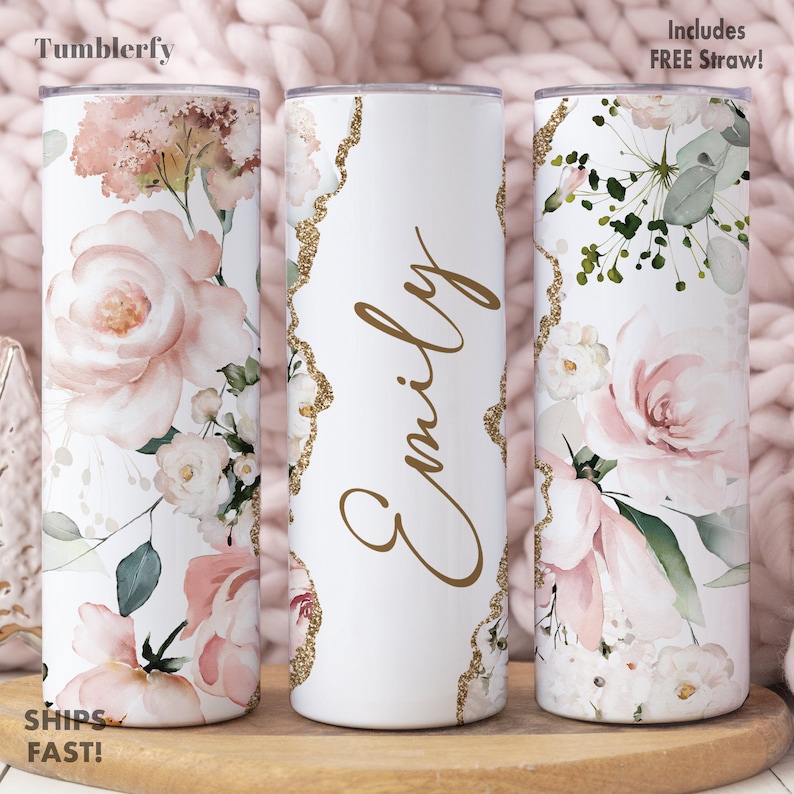 May include: Personalized white tumbler with a gold glitter design and floral pattern. The tumbler has the name "Emily" written in gold script.