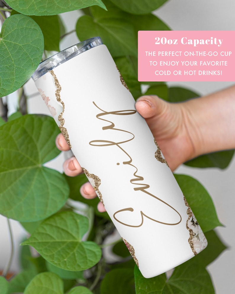 May include: White tumbler with a gold glitter design and the name "Emily" written in cursive. The tumbler is 20 ounces and is perfect for cold or hot drinks.