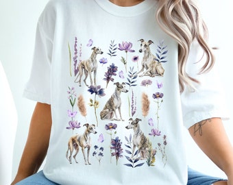 May include: White t-shirt with a floral print featuring Whippet dogs in various poses. The flowers are in shades of purple, pink, and blue.