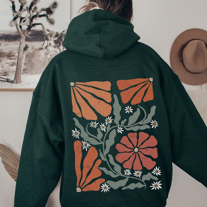 May include: A dark green hooded sweatshirt with a floral design on the back. The design features orange, red, and white flowers with green leaves.